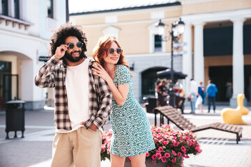 Smiling beautiful redhead  woman and her handsome boyfriend. Model in casual summer clothes. Happy cheerful family. Female having fun. Couple posing in the street at sunny day