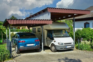 Carport aus lasiertem/lackiertem Holz im Einfahrtsbereich eines Wohnhauses