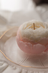 handmade candle in the shape of a flower on a light background, space for text