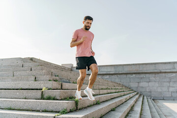 A man in a pink t-shirt and black shorts carefully descends the vast stone steps, engaging in a...