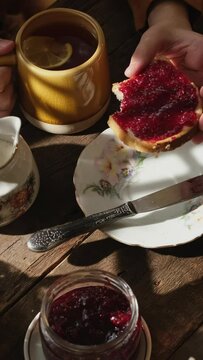 Vertical video. Morning breakfast. Drinking tea, eating sandwich with berry jam