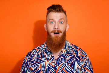 Photo of impressed funky guy dressed print shirt big eyes open mouth isolated orange color background