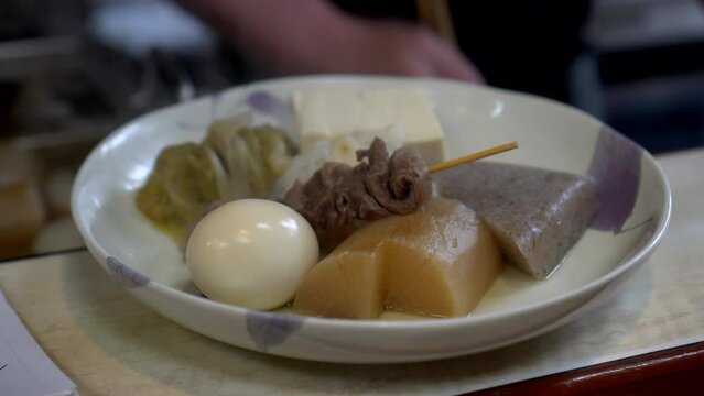 Japanese warm autumn boild dish oden boil fish cakes chef cutting tofu and ingredients for serving