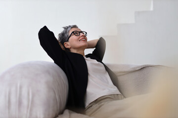 A senior adult enjoys rest and relaxation on the sofa, embodying peacefulness and calm in the...
