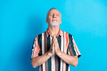 Photo of handsome dreamy senior man wear striped stylish clothes praying isolated on blue color...