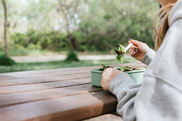 Woman sitting at an outdoor picnic area resting with a plate of salad