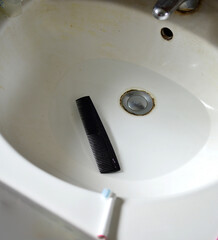 Hair comb in water is soaked in the sink to remove the grease between the teeth of the comb with an...