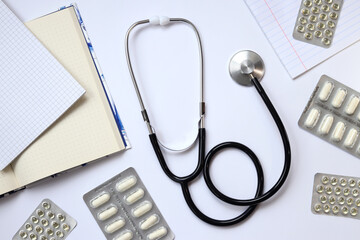 Stethoscope, notepads and medicines on a light background, top view. Cardiology and healthcare...