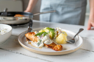 Fresh cooked healthy homemade meal with salmon fillet, boiled potatoes and light yogurt herb sauce
