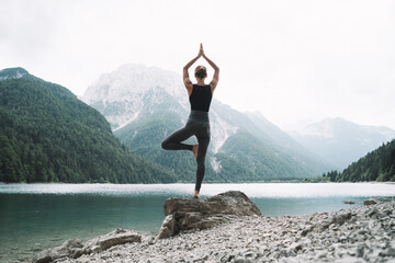 Young woman is practicing yoga at mountain lake. - 789344892