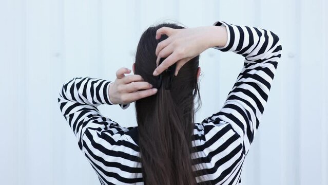 Back view woman with hair clips. Brunette woman pinning long straight hair clip click clack white background. Step-by-step tutorial on how to make hairstyle with your own hands.Modern stylish hairpin.