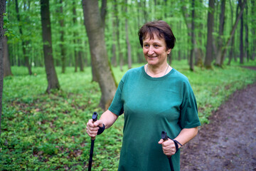 elderly woman is engaged in Nordic walking with sticks in the spring forest