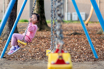 Little girl playing on the swing at the playground 