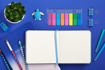 Empty notebook page for your text with blue and mint school and office stationery on blue background. Eraser in form of turtle. Flatly.