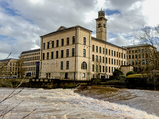 New Mill Saltaire which was built in 1868 on the site of an earlier mill overlooking the weir on the River Aire and includes an Italianate chimney is now used as flats and by the NHS as offices