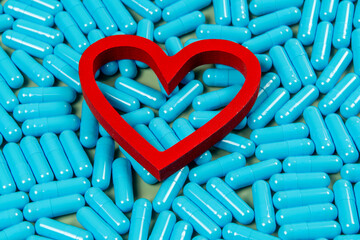 heart shape and blue capsules. Importance of medication treatment