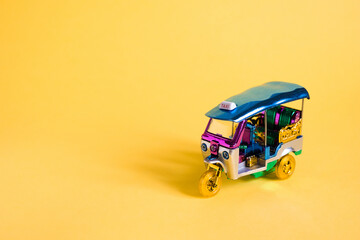 Model Toy tuk tuk isolated on yellow background. Thai traditional taxi in Bangkok Thailand....