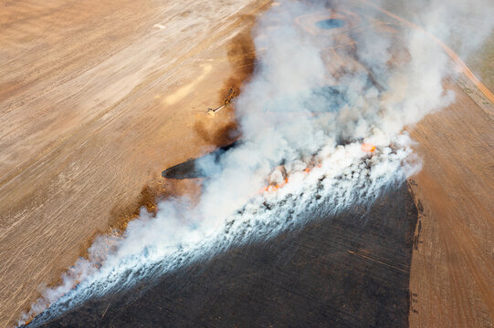 aerial view of stubble fire with white smoke and blackened land