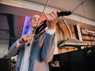 Violinist engages with electric violin, passion in his expression, in vibrant venue lighting.
