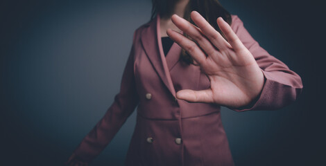 A businesswoman in a pink suit holds her hand out to stop something.
