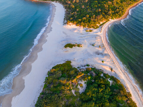 Aerial view of a narrow sand spit with forest on either side