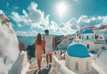 Poster Young couple in love walking along the stairs of Oia, Santorini island with blue domes and white church buildings on Greek volcano landscape © Kien