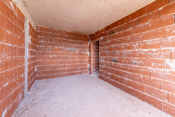 Unfinished room interior of building under construction. Brick red walls. New home.