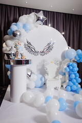 Blue photo zone with balloons, wings and cake on birthday party - obrazy, fototapety, plakaty