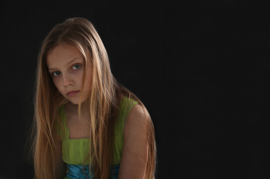 portrait of a sad little girl looking at the capera on black background