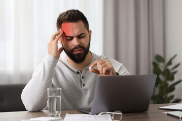Man with pill suffering from headache at workplace indoors