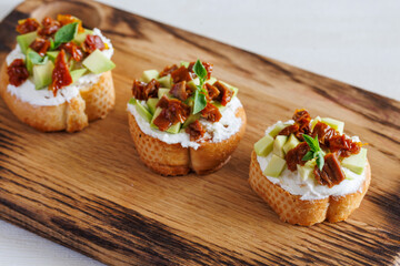 selective focus of italian bruschetta with dried tomatoes, avocado, cream cheese and herbs.