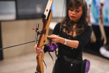 A beginner Asian woman is engrossed in learning archery, trying her hand at this challenging sport...
