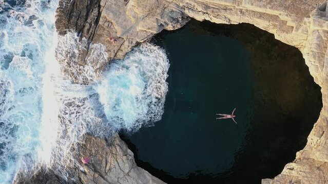 Slow motion aerial view of girl floating in Giola natural sea pool Thassos island, Greece
