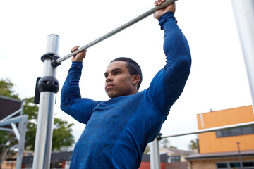 Young Indigenous man doing pulls ups at outdoor park