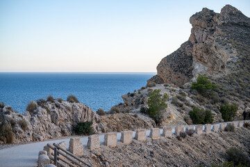 A winding coastal road meanders along rugged terrain, leading the eye to the merging of sea and sky...