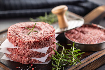 Fresh raw ground beef patties with rosemary salt and pepper made in a meat form on a cutting board - 789410829