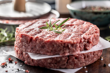Fresh raw ground beef patties with rosemary salt and pepper made in a meat form on a cutting board - 789411087