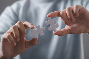 Businessman hand holding jigsaw puzzle trying to connect couple puzzle piece. Solution and solve...