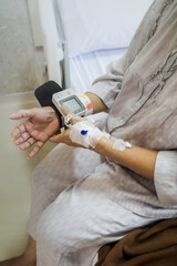 Mature adult female patient using digital blood pressure and heart rate measuring device on her wrist