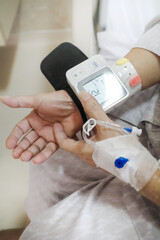 Mature adult female patient using digital blood pressure and heart rate measuring device on her wrist