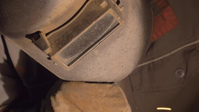 Metallurgy industry specialist deals with welding process. Metallurgy industry specialist combining the product parts using a welding torch. Metallurgy industry specialist wearing a protective helmet.