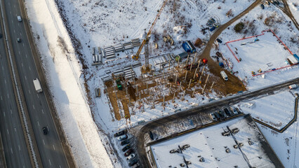 Drone photography construction site covered by snow and heavy equipment working during winter day