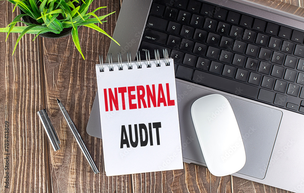 Poster internal audit text on notebook with laptop, mouse and pen