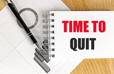TIME TO QUIT text on notebook with chart on wooden background