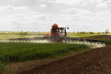 Tractor spraying pesticides wheat field. - 789417408