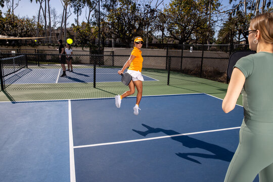 Pickleball players on an outdoor court playing the popular game. The sport is similar to tennis and allows for a diverse range of people to play. 