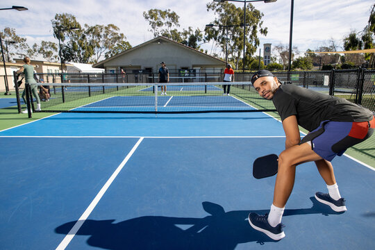 Pickleball players on an outdoor court playing the popular game. The sport is similar to tennis and allows for a diverse range of people to play. 