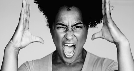 Angry Young African American woman screaming at camera while gesturing with hands, one epxressive...