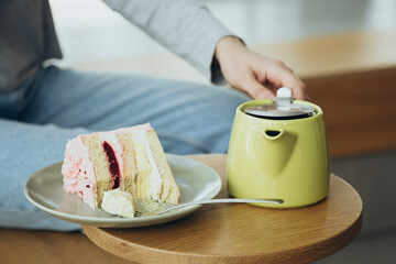 A piece of cake and a green teapot on a table in a cafe, a delicious dessert.