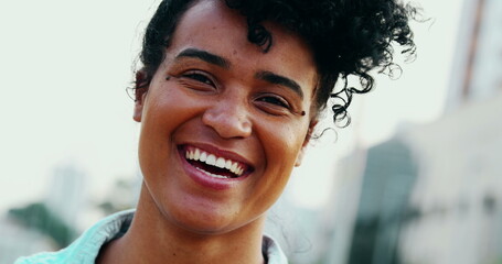 Happy Young African American woman laughing and smiling standing in urban setting close-up face....